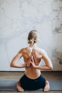 A young woman meditating indoors in reverse prayer pose, enhancing wellness and mindfulness.